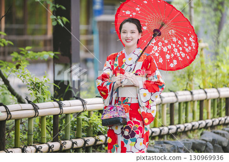 A woman in a kimono sightseeing with a Japanese umbrella A woman in a kimono sightseeing with a Japanese umbrella 130969936