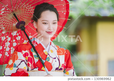 一個穿著和服的年輕女子拿著一把日本雨傘 一個穿著和服的年輕女子拿著一把日本雨傘 130969962
