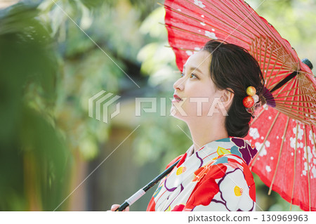 一個穿著和服的年輕女子拿著一把日本雨傘 130969963