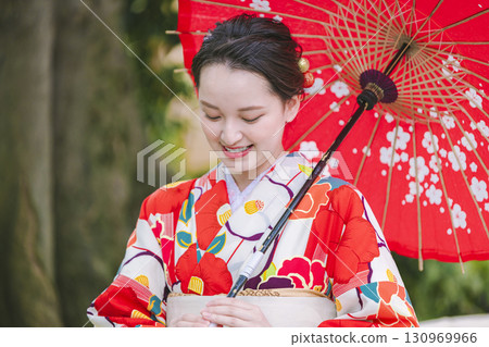 一個穿著和服的年輕女子拿著一把日本雨傘 130969966