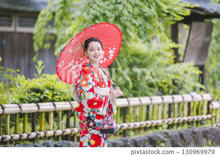A woman in a kimono sightseeing with a Japanese umbrella A woman in a kimono sightseeing with a Japanese umbrella 130969979