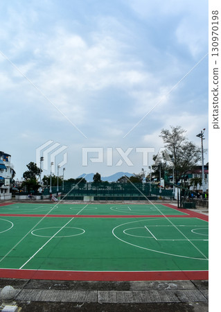 The scene of outdoor basketball court with seascape and skyscape. Outdoor sports and recreation court. Nobody in the basketball court in the sunny day. Sports and recreation concept. 130970198