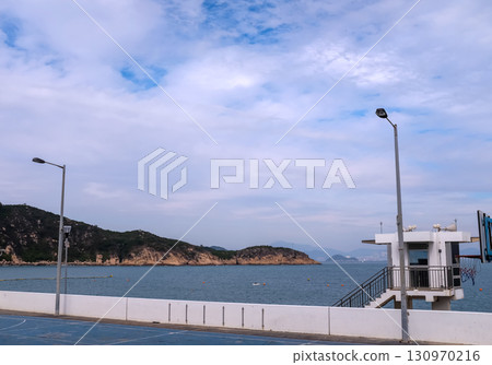 The scene of outdoor basketball court with seascape and skyscape. Outdoor sports and recreation court. Nobody in the basketball court in the sunny day. Sports and recreation concept. The scene of outdoor basketball court with seascape and skyscape. Outdoor sports and recreation court. Nobody in the basketball court in the sunny day. Sports and recreation concept. 130970216
