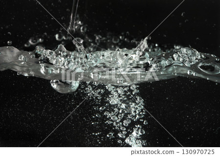Water splashing as it's poured into aquarium tank, black background Water splashing as it's poured into aquarium tank, black background 130970725