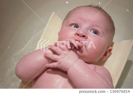 Infant baby boy washed in small bath tub, view from above 130970854
