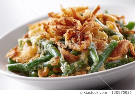 Classic Thanksgiving green bean casserole in a round ceramic baking dish, isolated on white background 130970925