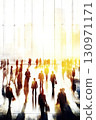 A blurry crowd of business people in a large, bright business hall. A dynamic scene unfolds in the bright business hall, filled with a blurry crowd of professionals exchanging ideas and networking. 130971171