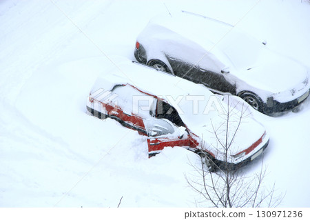 Man trying to free his car from snowy captivity. Parked cars covered with snow Man trying to free his car from snowy captivity. Parked cars covered with snow 130971236