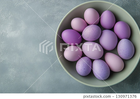 Decorative Purple Eggs Arranged in a Bowl on a Grey Background. 130971376