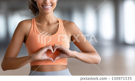 Woman in workout attire expressing love with a heart gesture Woman in workout attire expressing love with a heart gesture 130971535