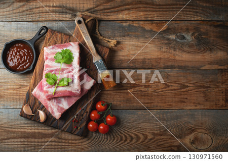Raw pork ribs with spices, salt and rosemary on dark wooden background 130971560