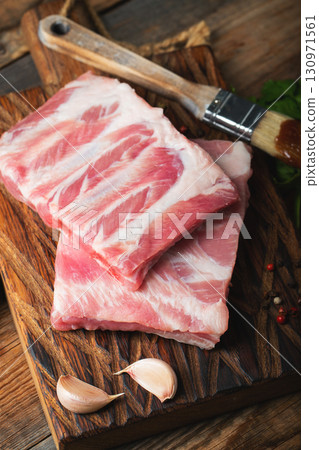 Raw pork ribs with spices, salt and rosemary on dark wooden background 130971561