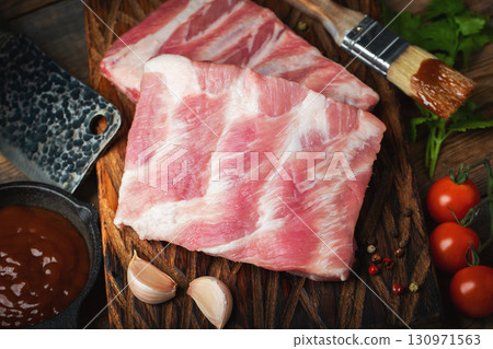 Raw pork ribs with spices, salt and rosemary on dark wooden background Raw pork ribs with spices, salt and rosemary on dark wooden background 130971563