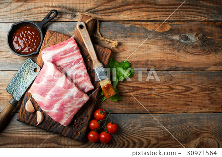 Raw pork ribs with spices, salt and rosemary on dark wooden background 130971564