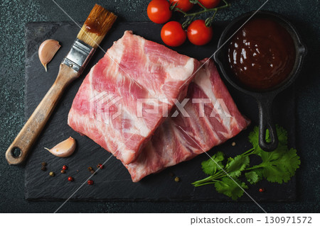 Raw meat. Raw pork ribs from the back with meat on a black background. background image 130971572