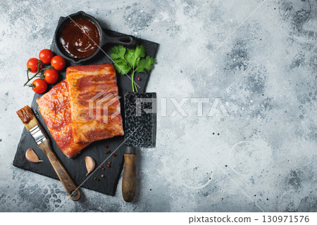 Ready for BBQ raw pork spare ribs with barbecue sauce. Black background. Top view 130971576