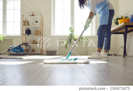 Young cleaner or housewife doing housework and mopping the floor in the living room 130971675