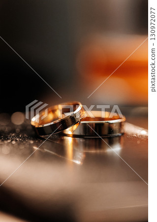 Two gold wedding rings on mirror with warm romantic light and soft background blur 130972077