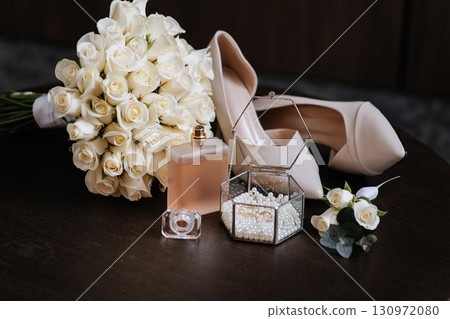 Bridal accessories with bouquet, shoes, perfume and wedding rings on elegant table Bridal accessories with bouquet, shoes, perfume and wedding rings on elegant table 130972080
