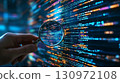 Someones hand holding magnifying glass close to screen with digital code on it. 130972108
