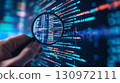 Someones hand holding magnifying glass close to screen with digital code on it. 130972111