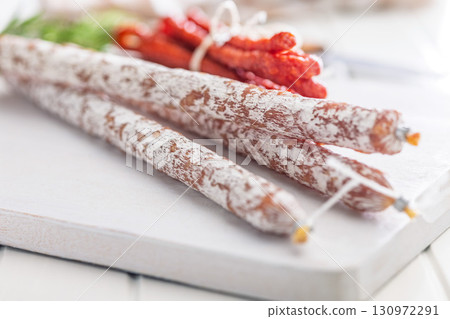 Fuet sausage with mold and smoked kabanos mini salami on white cutting board. 130972291