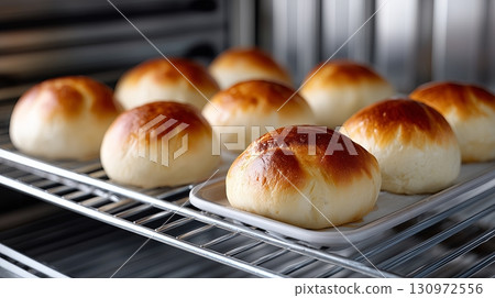 Freshly baked bread rolls cooling on a wire rack in a kitchen Freshly baked bread rolls cooling on a wire rack in a kitchen 130972556