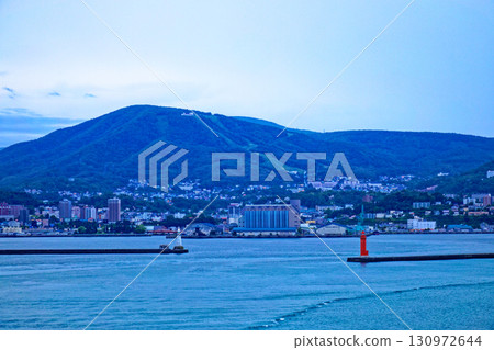 A view of the lighthouse and Otaru cityscape from the Shin Nihonkai Ferry "Azalea" departing from Otaru Port 130972644