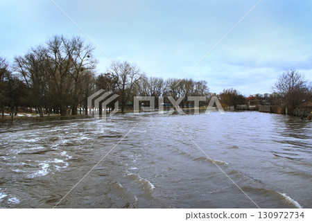 Flooding of river in spring in town during melting of snow. Natural disaster Flooding of river in spring in town during melting of snow. Natural disaster 130972734