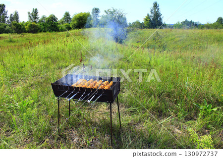 Cooking of shashliks from potatoes and bacon in summer field 130972737
