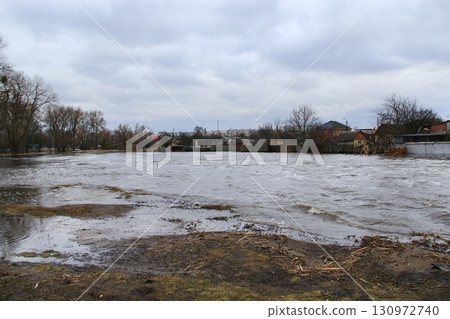 Flooding of river in spring in town during melting of snow. Natural disaster Flooding of river in spring in town during melting of snow. Natural disaster 130972740