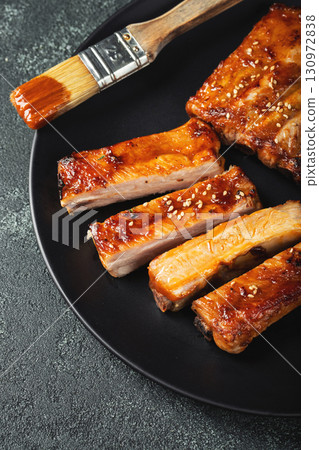 Hot grilled spare ribs from a summer BBQ served on a plate with sauce. Top view. Copy space Hot grilled spare ribs from a summer BBQ served on a plate with sauce. Top view. Copy space 130972838