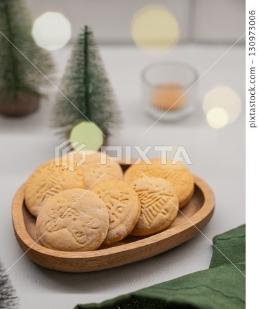 Festive gingerbread cookies with festive patterns on a wooden plate on a light background Festive gingerbread cookies with festive patterns on a wooden plate on a light background 130973006