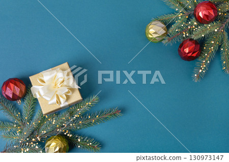 Christmas dark blue background with green Christmas tree branches and red, yellow decorative balls, gift box with space for text in the center for greetings, suggestions, labels, and your design. 130973147