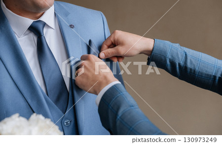 Close up of groom getting ready, adjusting pocket square in blue suit before wedding Close up of groom getting ready, adjusting pocket square in blue suit before wedding 130973249