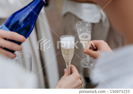 Pouring sparkling wine into plastic flutes during outdoor celebration toast Pouring sparkling wine into plastic flutes during outdoor celebration toast 130973255