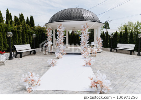 Elegant wedding ceremony setup with floral arch in outdoor luxury garden venue 130973256