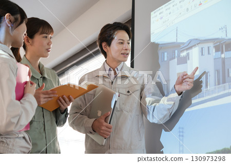 Three men and women discussing housing development in front of a screen 130973298