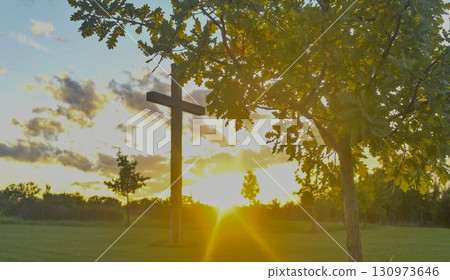 A large Christian cross in the scenery of a landscape. A Christian cross lighted by the setting sun. The concept of religion and Christianity. 130973646