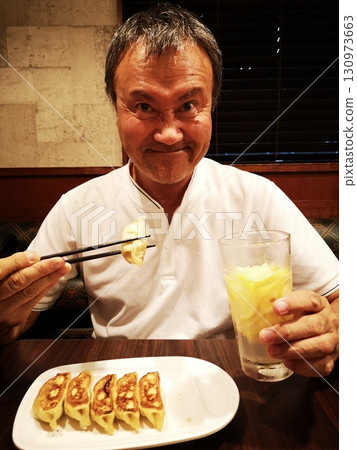 A man drinking lemon sour with gyoza 130973663