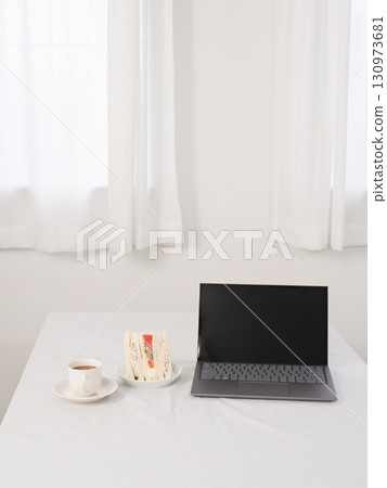 Laptop, cafe au lait and sandwich on a white table Laptop, cafe au lait and sandwich on a white table 130973681
