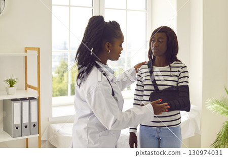 Doctor supporting female patient with broken arm and giving her consultation in medical office. Doctor supporting female patient with broken arm and giving her consultation in medical office. 130974031