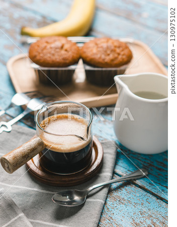 A cup of hot black coffee, Espresso, fresh baked muffins. Banana cupcake close-up as dessert for coffee break. Top view. refreshing morning and day A cup of hot black coffee, Espresso, fresh baked muffins. Banana cupcake close-up as dessert for coffee break. Top view. refreshing morning and day 130975102