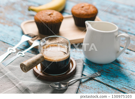 A cup of hot black coffee, Espresso, fresh baked muffins. Banana cupcake close-up as dessert for coffee break. Top view. refreshing morning and day 130975103