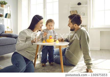 Young family with a daughter playing with rubber ducks at home together. 130975853