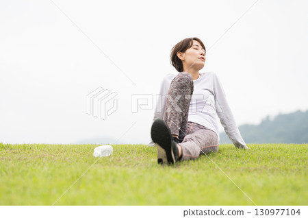 A woman taking a break after exercise on the grass A woman taking a break after exercise on the grass 130977104
