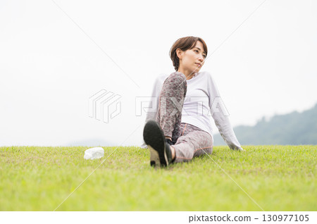 A woman taking a break after exercise on the grass A woman taking a break after exercise on the grass 130977105