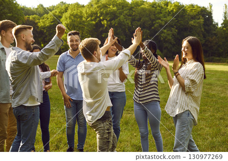 Cheerful joyful young multiethnic friends laughing loudly and giving each other high five. 130977269