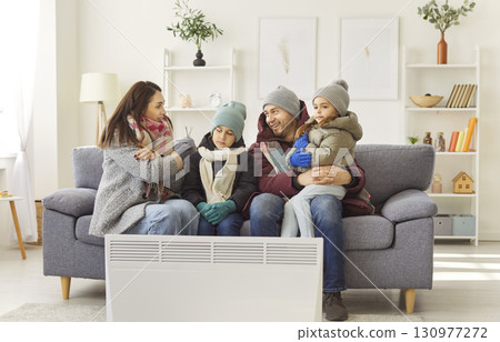Unhappy family, parents and small children freezing at home wearing winter warm clothes Unhappy family, parents and small children freezing at home wearing winter warm clothes 130977272