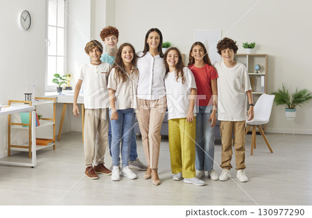 Portrait Of Happy Students Standing With Teacher In School Classroom Portrait Of Happy Students Standing With Teacher In School Classroom 130977290